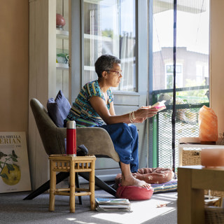Vrouw in haar appartement een boek aan het lezen in de zon